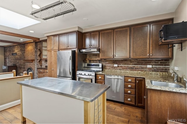 kitchen with light stone countertops, appliances with stainless steel finishes, dark hardwood / wood-style floors, and sink