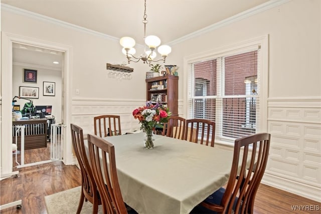 dining area with an inviting chandelier, hardwood / wood-style floors, and crown molding