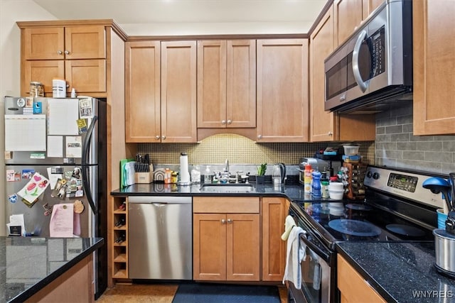 kitchen featuring dark stone counters, decorative backsplash, appliances with stainless steel finishes, and sink