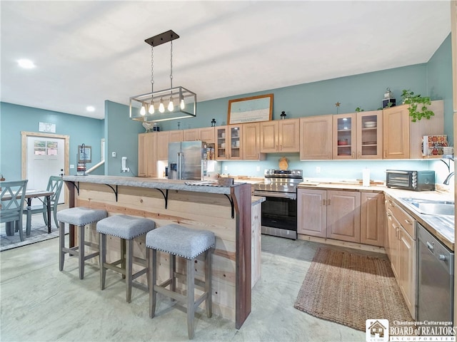 kitchen with sink, a kitchen island, stainless steel appliances, light brown cabinets, and decorative light fixtures