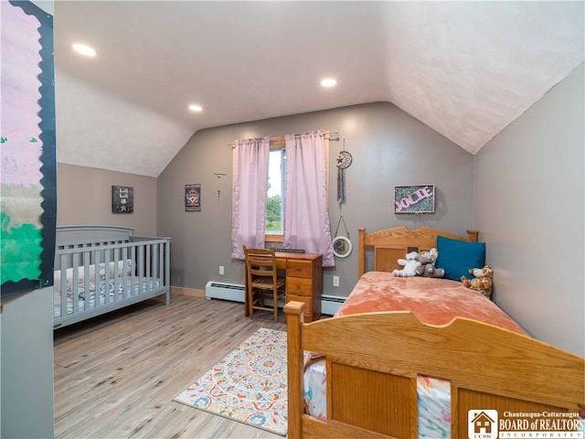 bedroom with vaulted ceiling, baseboard heating, and light hardwood / wood-style floors