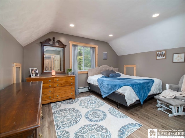 bedroom featuring wood-type flooring, vaulted ceiling, and a baseboard heating unit