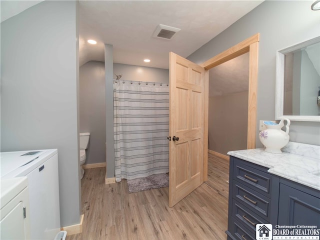 bathroom with vanity, curtained shower, wood-type flooring, separate washer and dryer, and toilet