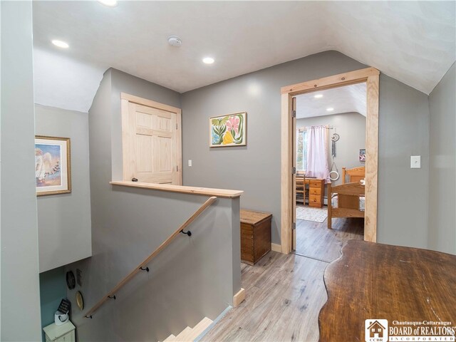 hallway with light hardwood / wood-style floors and vaulted ceiling