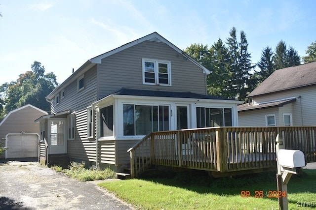 view of front facade featuring a garage, a front yard, a sunroom, a deck, and an outdoor structure