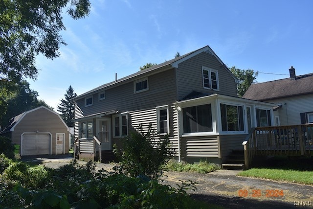 rear view of house featuring a garage, an outdoor structure, and a sunroom