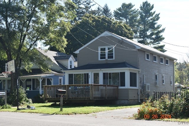 view of front of home featuring a wooden deck, a front lawn, and a sunroom