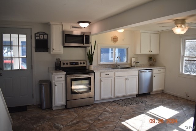 kitchen with stainless steel appliances, white cabinets, ceiling fan, and sink