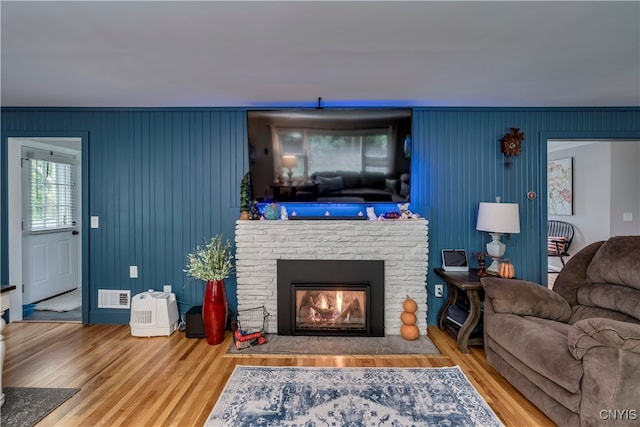 living room featuring wooden walls, hardwood / wood-style floors, and a fireplace