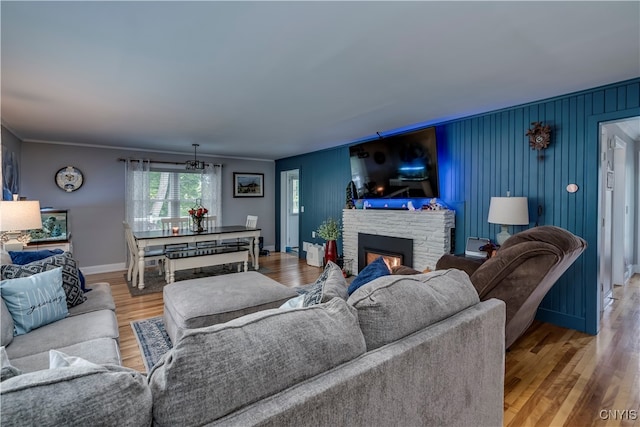 living room featuring a stone fireplace, crown molding, and hardwood / wood-style floors