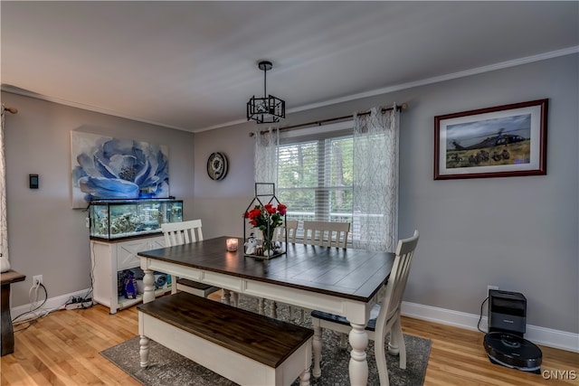 dining space featuring ornamental molding, a chandelier, and light hardwood / wood-style floors