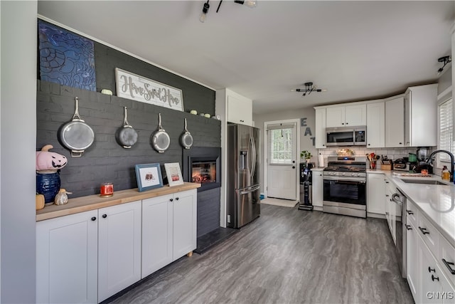 kitchen with white cabinets, appliances with stainless steel finishes, dark hardwood / wood-style floors, and sink