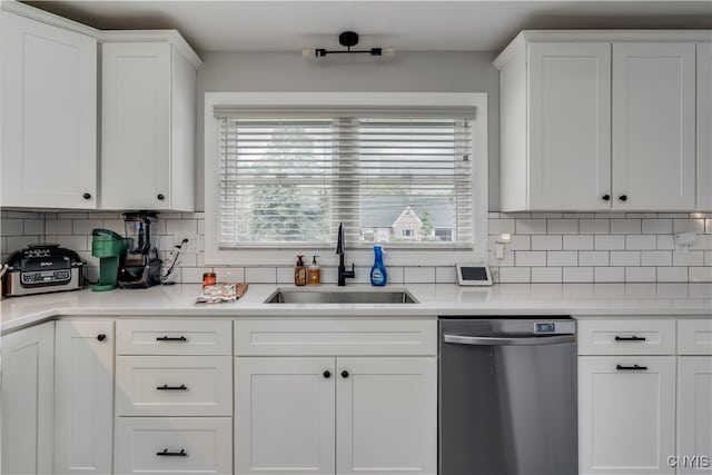 kitchen with decorative backsplash, white cabinetry, sink, and stainless steel dishwasher