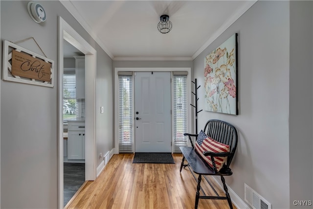 entryway with light hardwood / wood-style floors, a healthy amount of sunlight, and crown molding