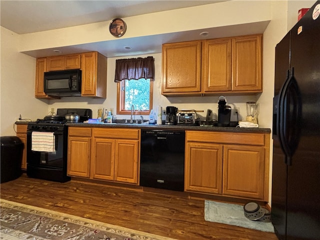 kitchen with dark hardwood / wood-style floors, sink, and black appliances