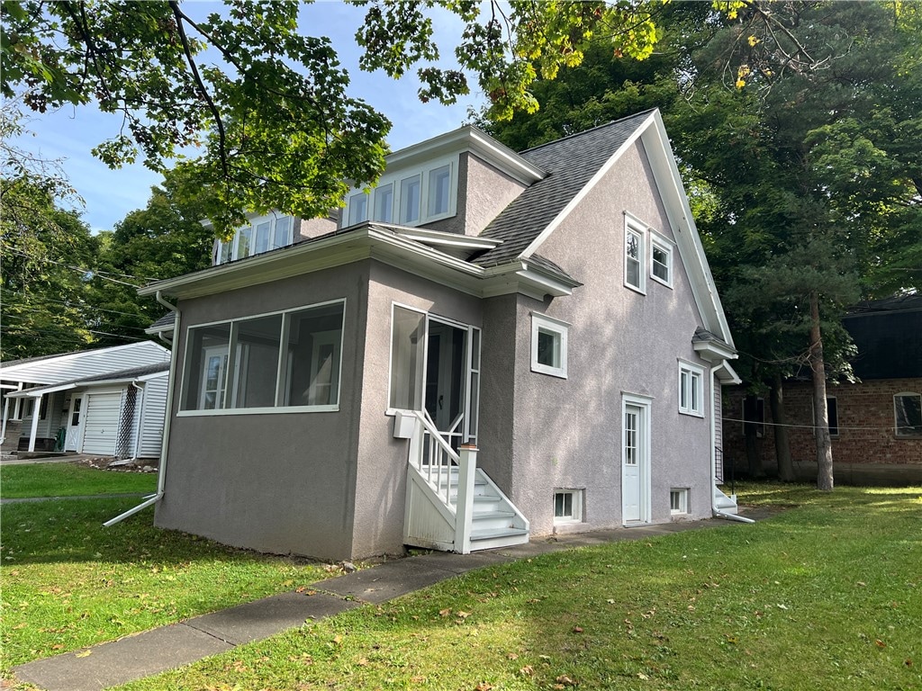 view of front of home featuring a sunroom and a front lawn