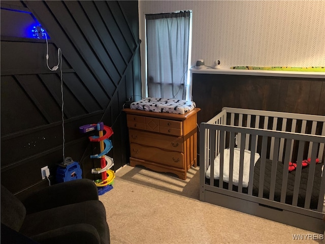 carpeted bedroom featuring a nursery area