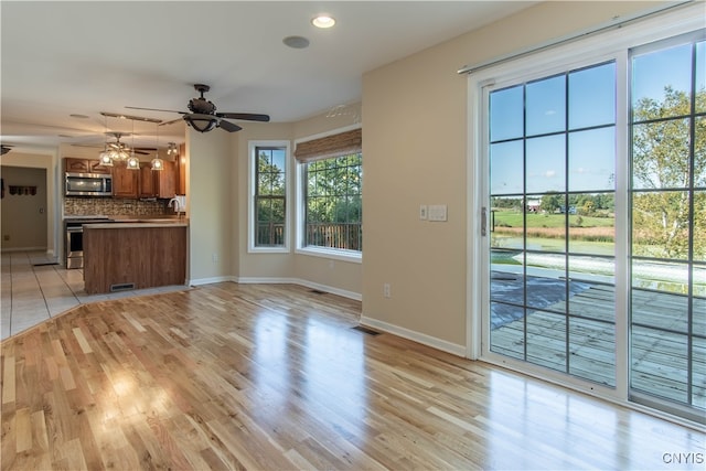 unfurnished living room featuring ceiling fan with notable chandelier, sink, and light hardwood / wood-style floors