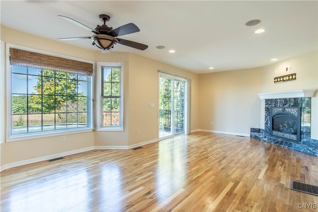 unfurnished living room with ceiling fan, a fireplace, and light hardwood / wood-style floors