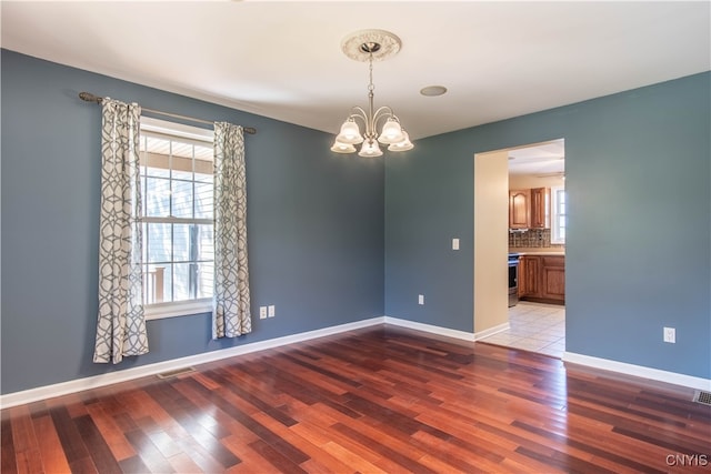 empty room with an inviting chandelier and light hardwood / wood-style flooring