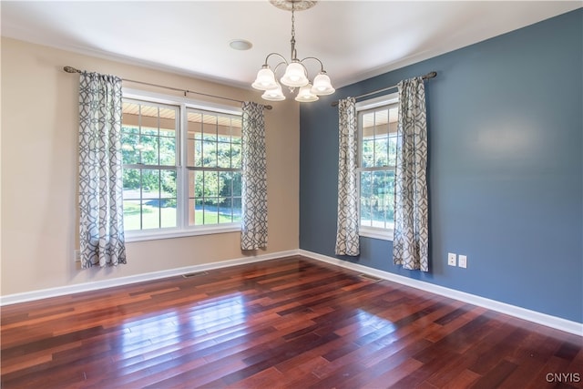 empty room with a wealth of natural light, a chandelier, and dark hardwood / wood-style floors