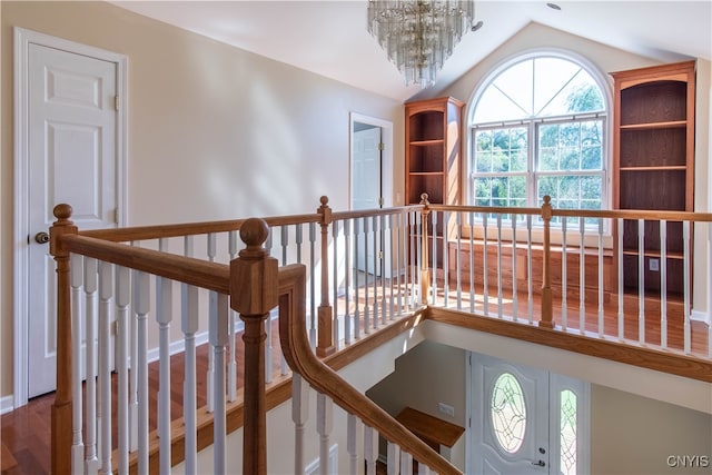 hall featuring hardwood / wood-style flooring, a notable chandelier, and vaulted ceiling