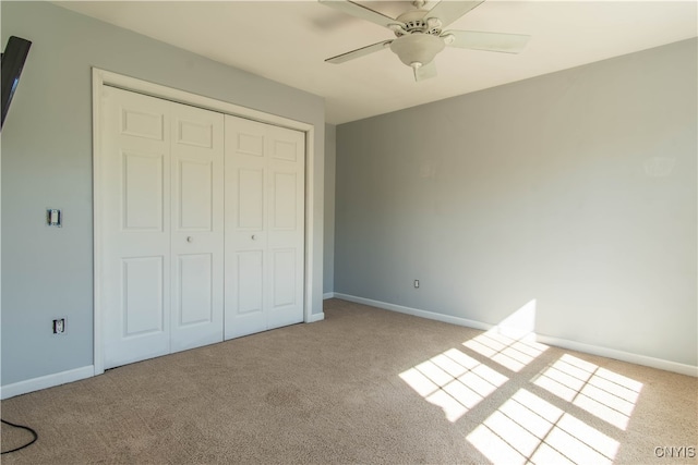 unfurnished bedroom featuring a closet, light colored carpet, and ceiling fan