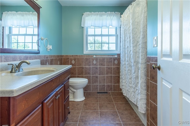 bathroom featuring toilet, a wealth of natural light, tile walls, and vanity