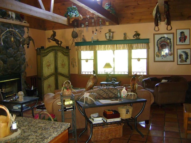 living room featuring vaulted ceiling with beams, a stone fireplace, dark tile patterned flooring, and plenty of natural light