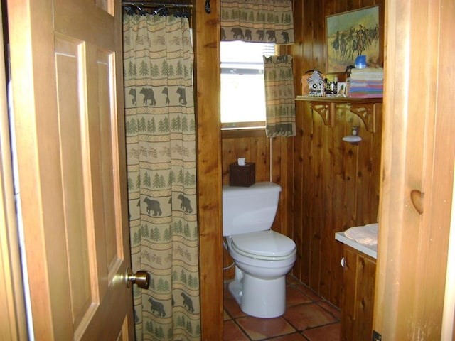 bathroom with wooden walls, tile patterned flooring, vanity, and toilet