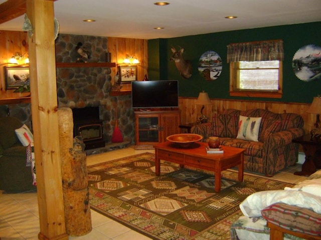 tiled living room with a fireplace, wood walls, and a wood stove