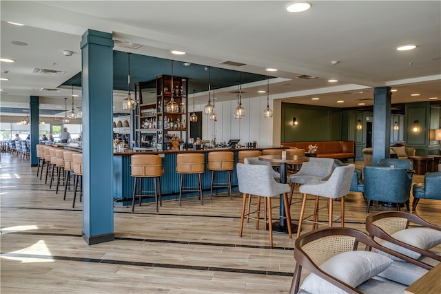 interior space with decorative columns, light hardwood / wood-style floors, and decorative light fixtures