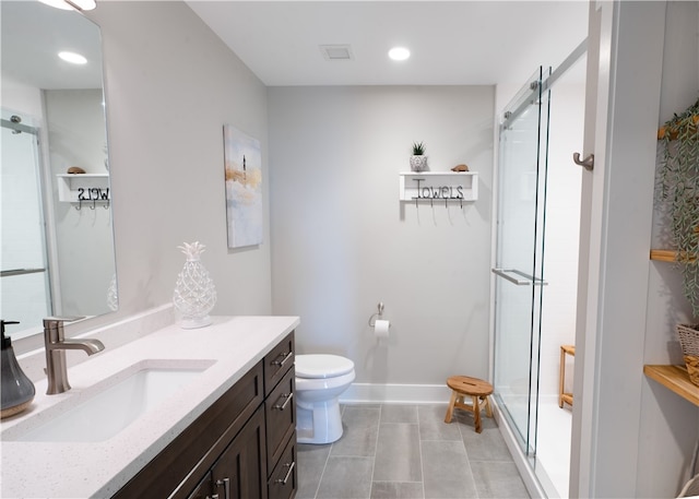 bathroom with tile patterned floors, a shower with door, vanity, and toilet