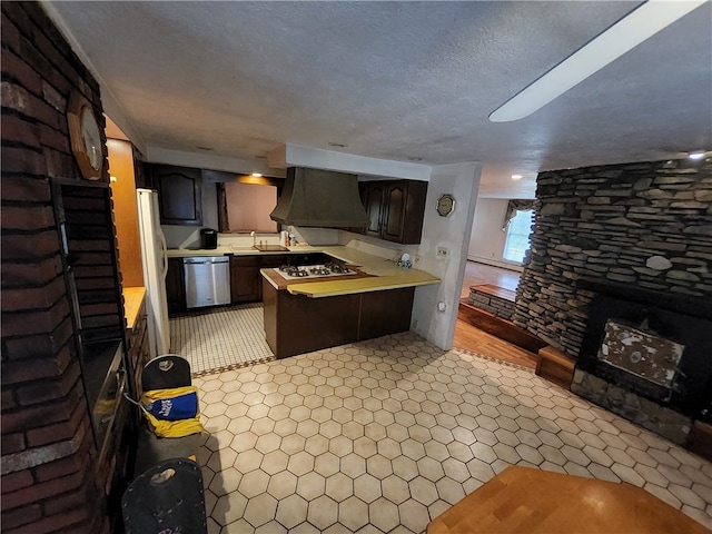 kitchen with ventilation hood, kitchen peninsula, a fireplace, white appliances, and dark brown cabinetry