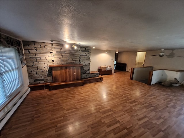 unfurnished living room featuring a baseboard radiator, hardwood / wood-style floors, a textured ceiling, and a fireplace