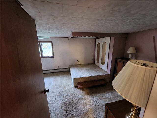 unfurnished bedroom with a baseboard radiator and carpet floors