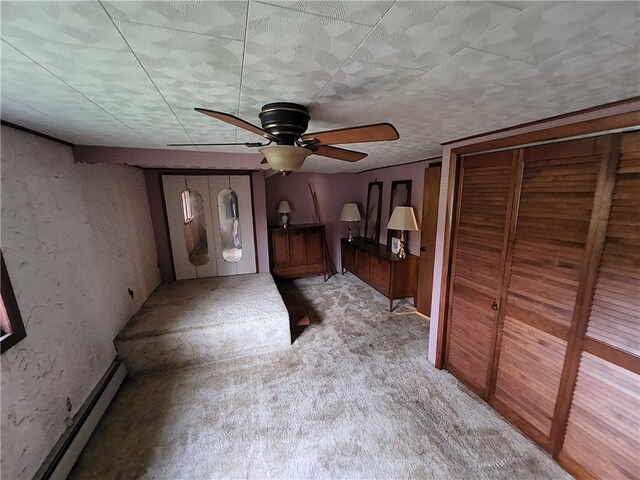 unfurnished bedroom with light carpet, ceiling fan, multiple closets, and a baseboard radiator