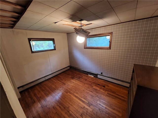 empty room with wood-type flooring, a baseboard radiator, and a wealth of natural light