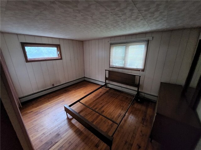 interior space with wood-type flooring, wood walls, and baseboard heating