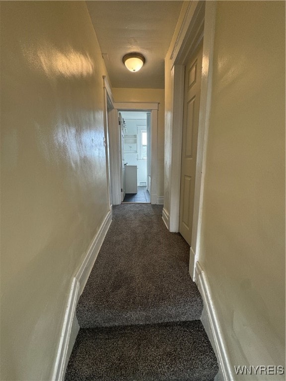 hallway featuring dark colored carpet