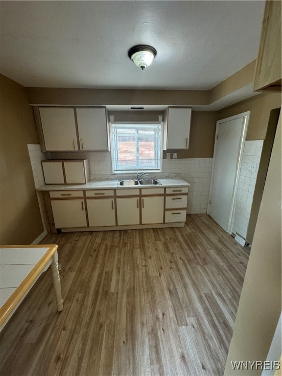 kitchen with light hardwood / wood-style floors, cream cabinets, sink, and tasteful backsplash