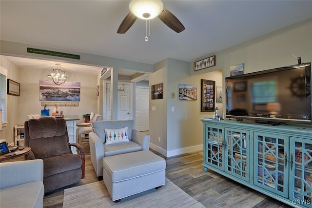 living room with hardwood / wood-style flooring and ceiling fan with notable chandelier