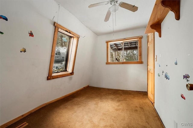 carpeted empty room featuring ceiling fan and a healthy amount of sunlight