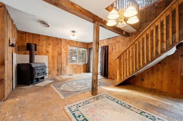 interior space featuring a wood stove, an inviting chandelier, and beam ceiling