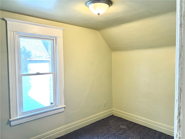 additional living space with lofted ceiling and dark colored carpet