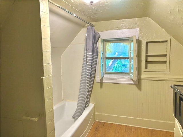 bathroom with lofted ceiling, hardwood / wood-style floors, and shower / bath combination with curtain