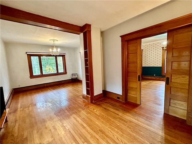 spare room featuring baseboard heating, light hardwood / wood-style flooring, and a chandelier