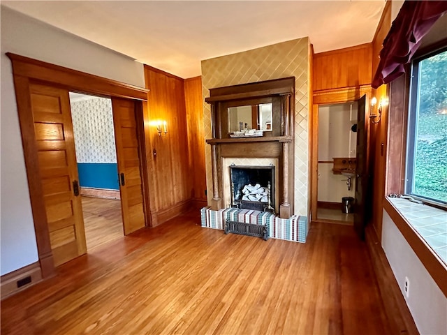 unfurnished living room featuring light wood-type flooring, a fireplace, and wood walls