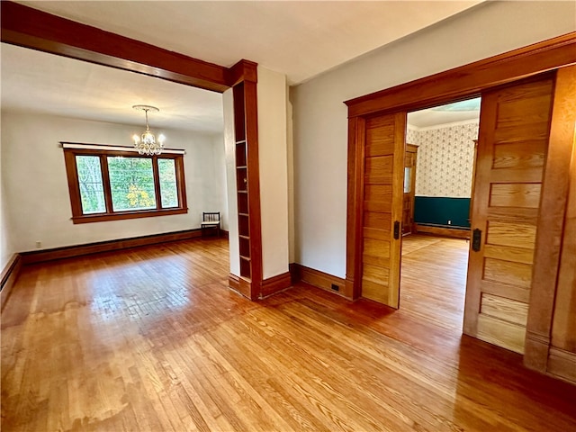 unfurnished room with baseboard heating, an inviting chandelier, and light hardwood / wood-style flooring