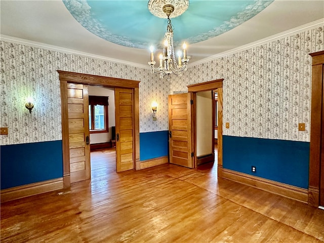 spare room with ornamental molding, a notable chandelier, and hardwood / wood-style floors